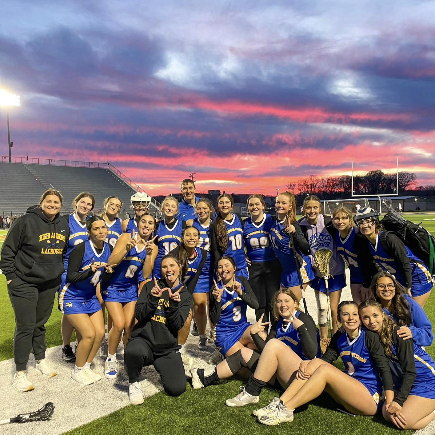 GPHS Lady Highlanders Lacrosse Team posing together on a field at sunset.