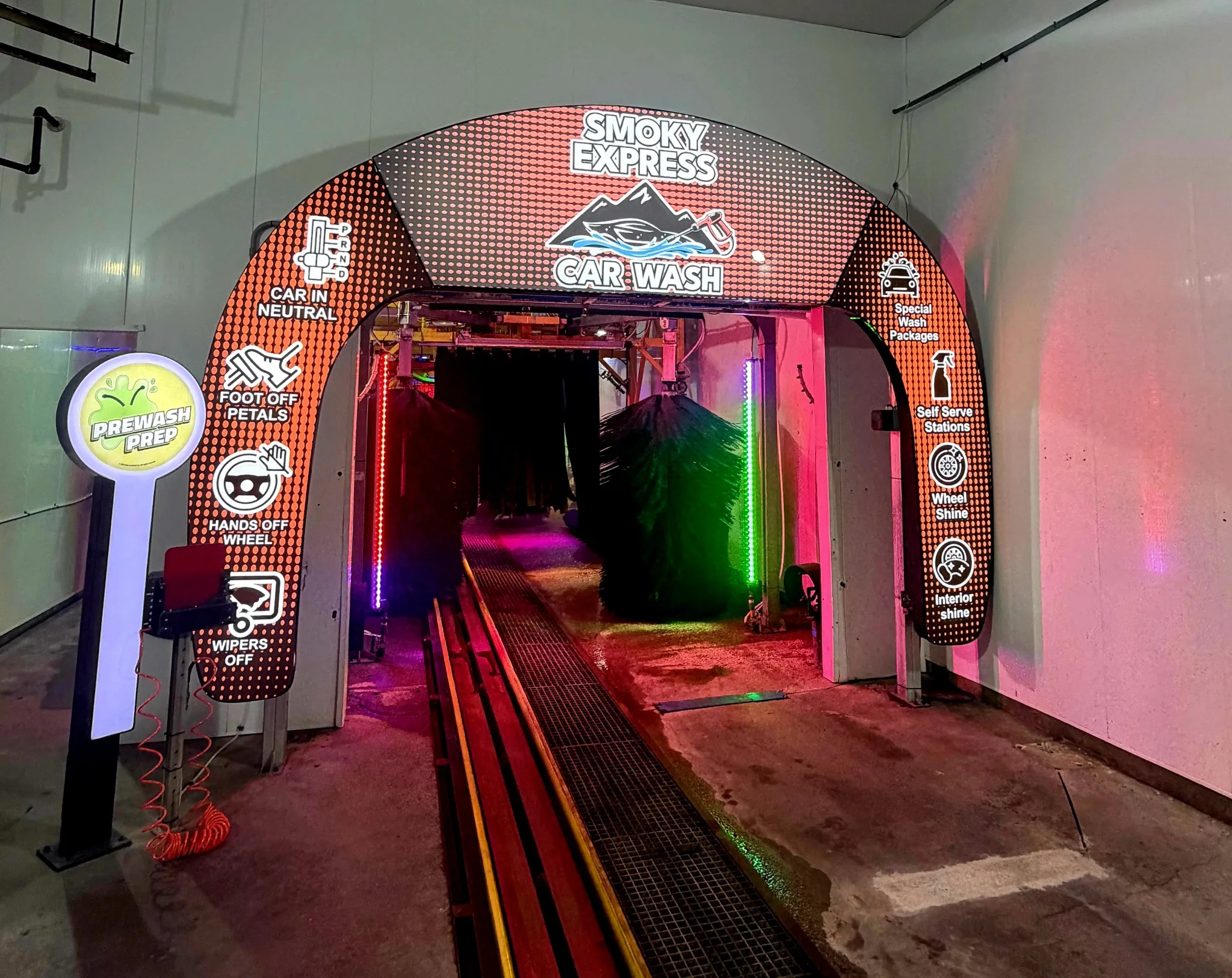 Interior tunnel entrance at Smoky Express Sevierville with prewash prep signage and wash equipment.